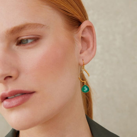 model wearing teardrop gold earrings with gold  beads  and green stone at bottom